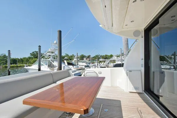 Slide: The Image of 2019 Prestige 460S yacht deck with wooden table, marina view, and sleek design. - 20