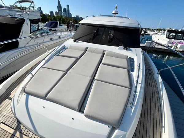 Slide: The Image of 2019 Prestige 460S yacht with sunbathing cushions, docked in a marina, city skyline in background. - 23