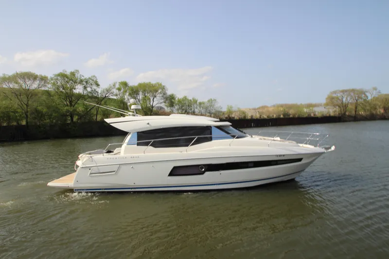 Slide: The Image of 2019 Prestige 460S yacht cruising on a calm river under a clear sky. - 7