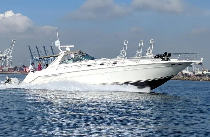 Slide: The Image of 1999 Sea Ray 500 Sundancer cruising on open water near industrial port. - 1