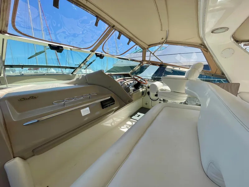 Slide: The Image of 1999 Sea Ray 500 Sundancer cockpit with beige seating and helm, featuring panoramic windows. - 32
