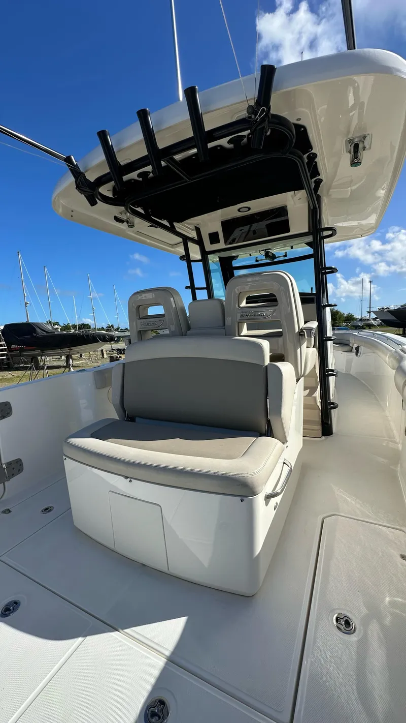 Slide: The Image of 2022 Boston Whaler 330 Outrage boat interior with seating and console under blue sky. - 11