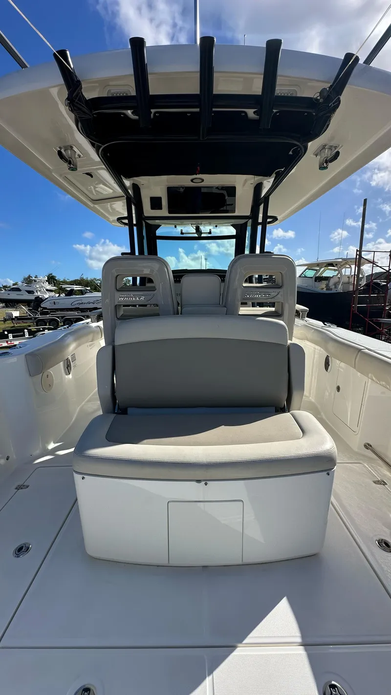 Slide: The Image of 2022 Boston Whaler 330 Outrage boat interior with seating and helm under clear blue sky. - 14