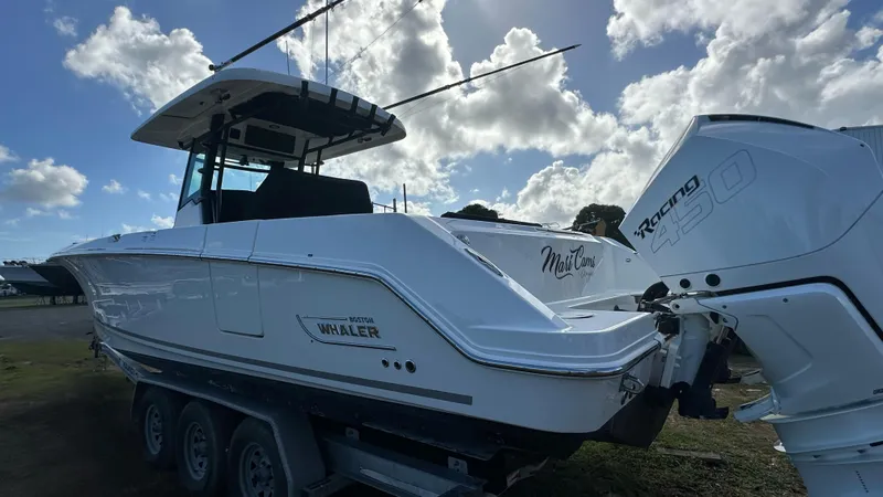 Slide: The Image of 2022 Boston Whaler 330 Outrage boat with triple-axle trailer and powerful outboard engines. - 16