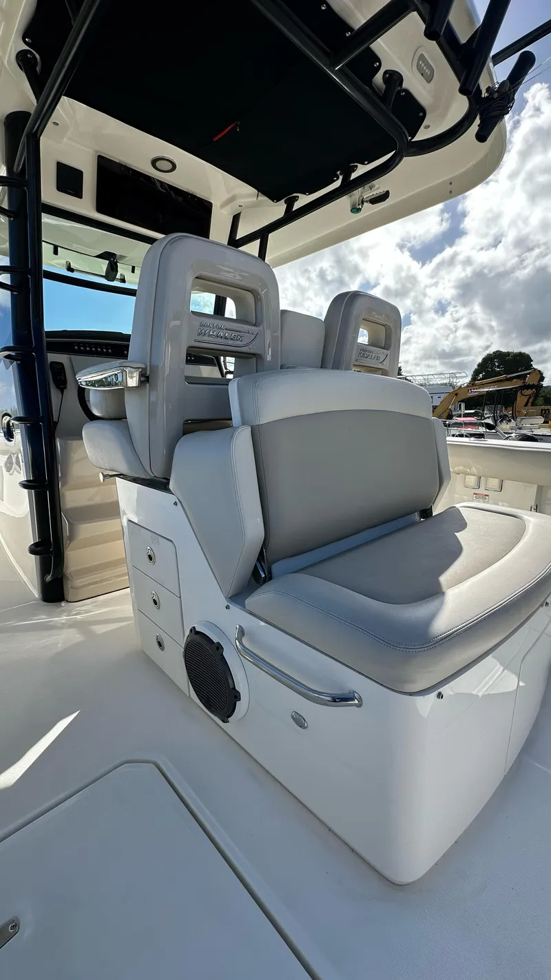 Slide: The Image of 2022 Boston Whaler 330 Outrage boat interior with cushioned seating and storage compartments. - 17