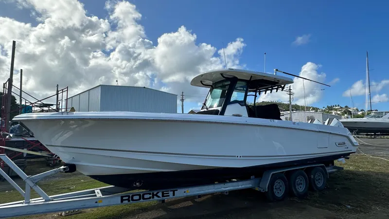 Slide: The Image of 2022 Boston Whaler 330 Outrage boat on trailer under blue sky. - 18