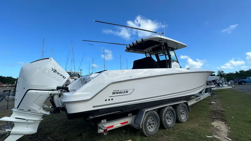 Slide: The Image of 2022 Boston Whaler 330 Outrage boat on trailer, side view under clear blue sky. - 4