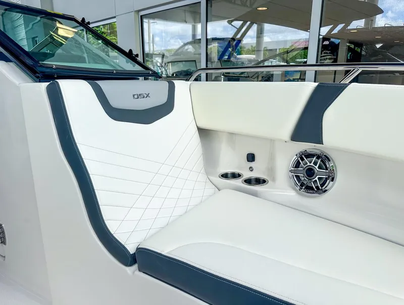 Slide: The Image of 2024 Chaparral 250 OSX OB boat interior with white and gray seating, speaker, and cup holders. - 34