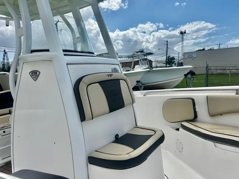 Slide: The Image of 2019 Tidewater 232 CC Adventure boat interior with cushioned seating under a blue sky. - 10