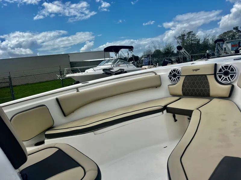 Slide: The Image of 2019 Tidewater 232 CC Adventure boat interior with cushioned seating under a blue sky. - 11
