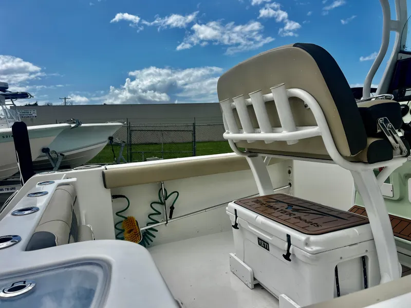 Slide: The Image of 2019 Tidewater 232 CC Adventure boat interior with seating and cooler under a blue sky. - 13