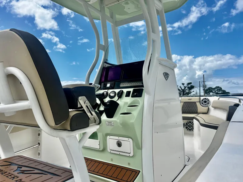 Slide: The Image of 2019 Tidewater 232 CC Adventure boat interior with helm, seating, and clear blue sky. - 14