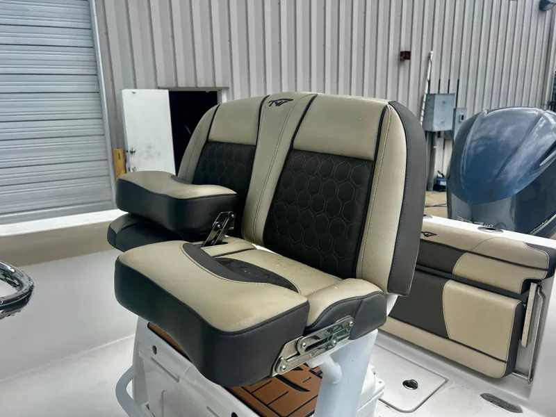 Slide: The Image of 2019 Tidewater 232 CC Adventure boat seat, beige and black upholstery, in a marina setting. - 7