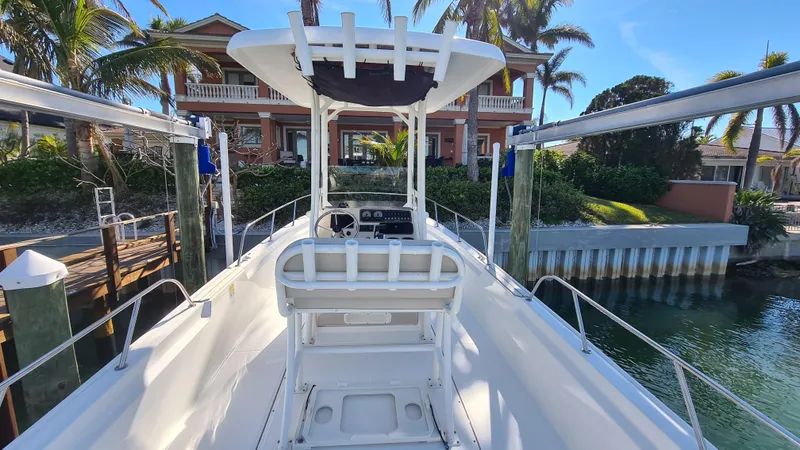 Slide: The Image of 2019 Boston Whaler 210 Montauk boat docked near a waterfront house with palm trees. - 11