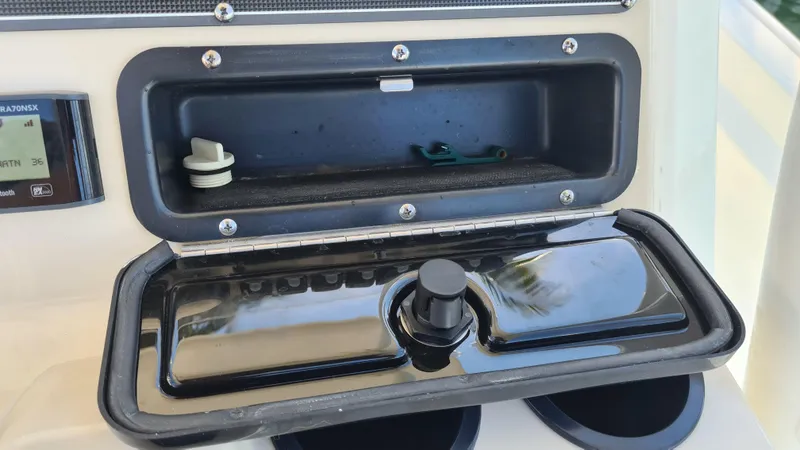 Slide: The Image of 2019 Boston Whaler 210 Montauk console storage compartment with open lid and visible controls. - 21