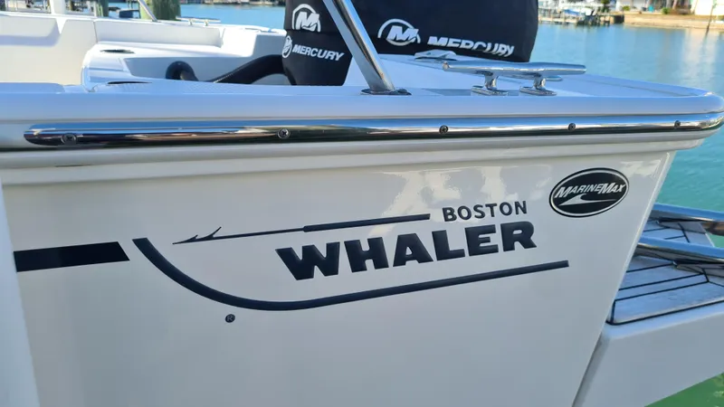 Slide: The Image of 2019 Boston Whaler 210 Montauk boat with Mercury branding, docked by the water. - 40