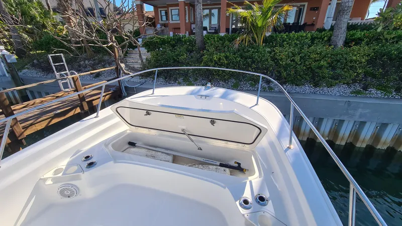 Slide: The Image of 2019 Boston Whaler 210 Montauk boat with open storage compartment, docked near waterfront home. - 8