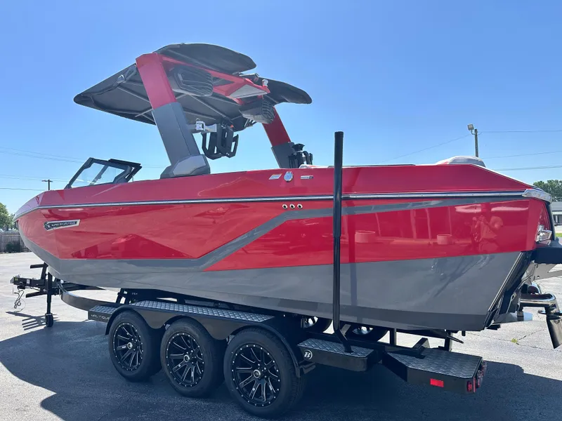Slide: The Image of 2025 Nautique Super Air Nautique G25 boat, red and gray, on a trailer in a parking lot. - 15