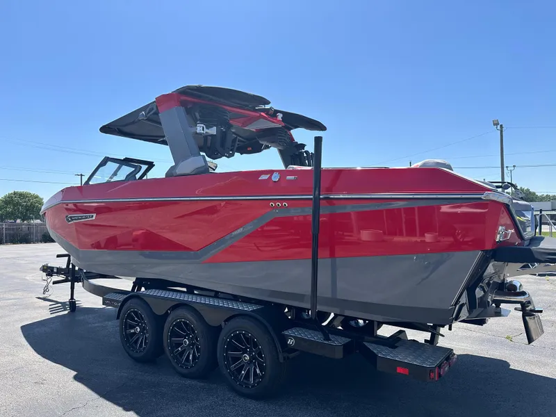 Slide: The Image of 2025 Nautique Super Air Nautique G25 boat, red and gray, on a trailer in a parking lot. - 9