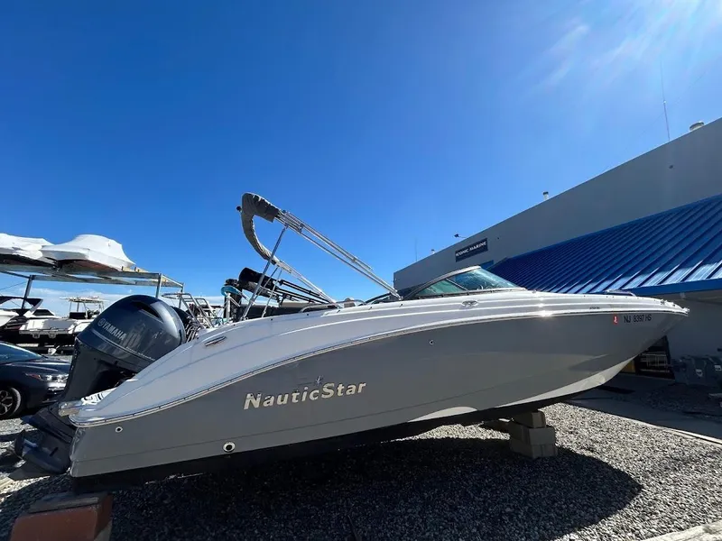 Slide: The Image of 2022 NauticStar 243DC Sport Deck boat displayed outdoors under clear blue sky. - 1