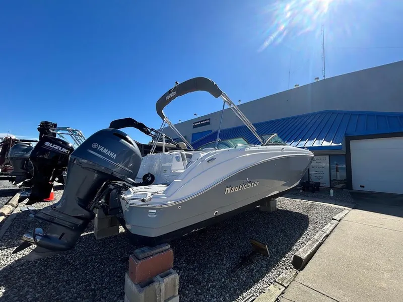 Slide: The Image of 2022 NauticStar 243DC Sport Deck boat with Yamaha engine, displayed outdoors. - 2