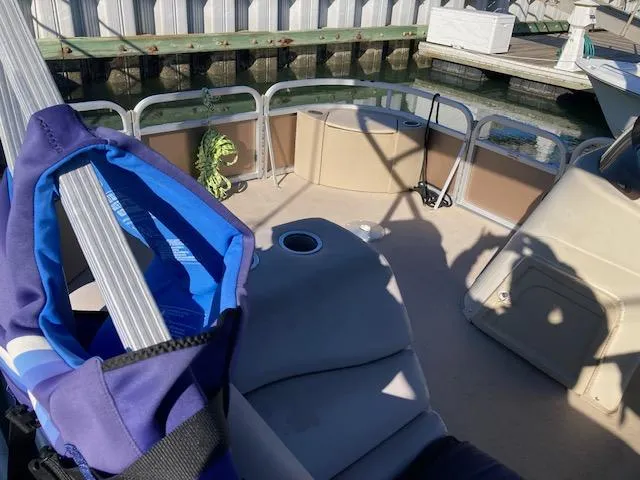 Slide: The Image of 2011 Bennington 20 GL boat interior with seating and life jacket, docked by a wooden pier. - 5