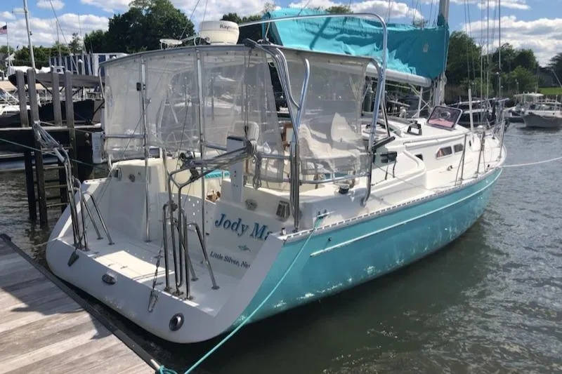 Slide: The Image of 2005 Shannon Shoalsailer docked, featuring turquoise hull and covered cockpit. - 10