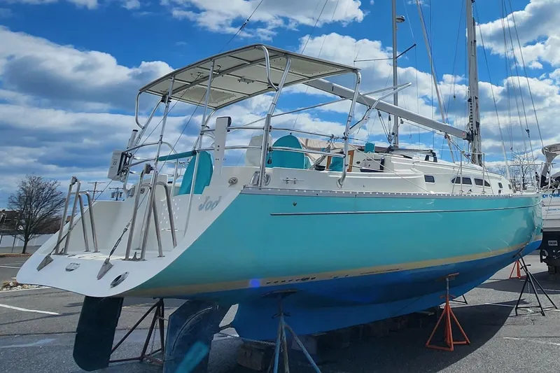 Slide: The Image of 2005 Shannon Shoalsailer sailboat on stands, turquoise hull, under a partly cloudy sky. - 29