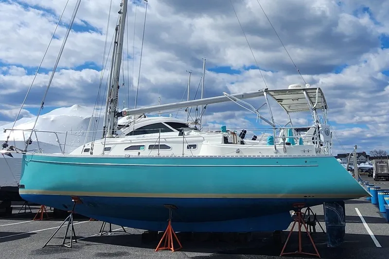 Slide: The Image of 2005 Shannon Shoalsailer sailboat on stands, turquoise hull, under a cloudy sky. - 4