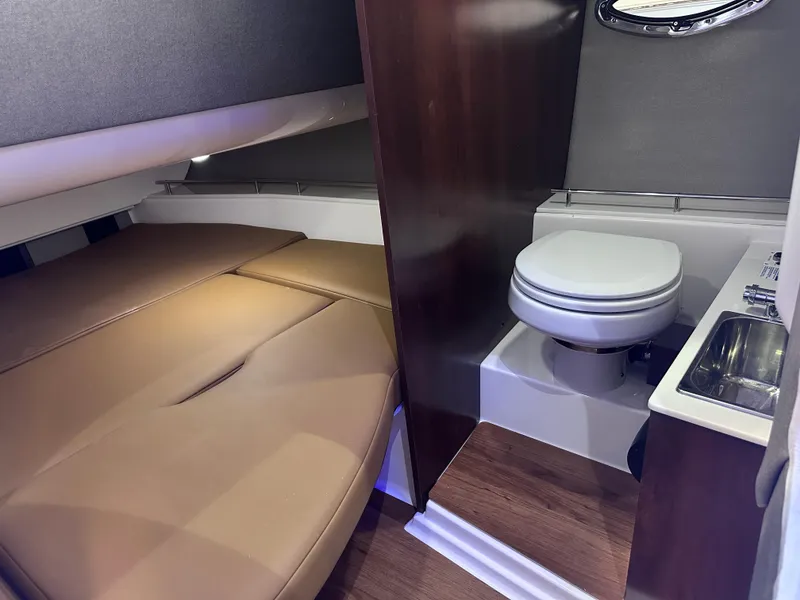 Slide: The Image of 2025 Chaparral 310 OSX cabin interior with bed, toilet, and sink. - 19