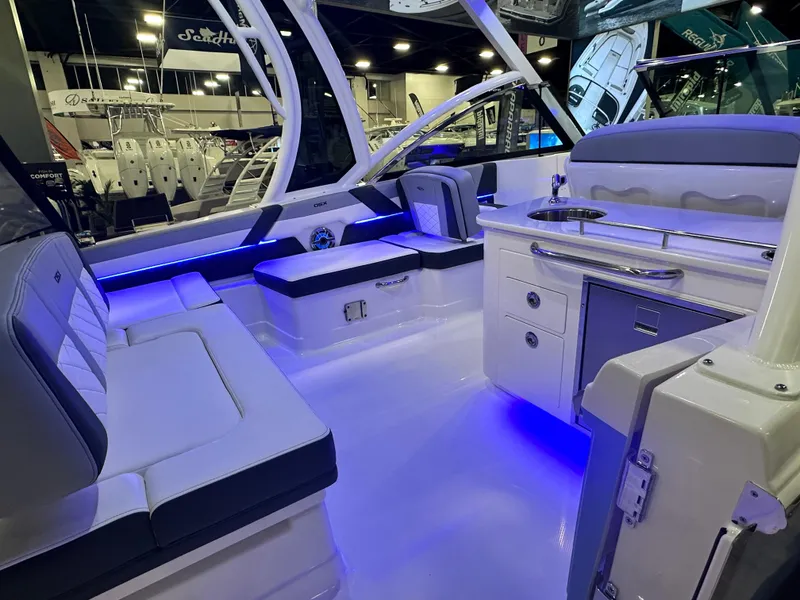 Slide: The Image of 2025 Chaparral 310 OSX boat interior with modern seating and ambient blue lighting. - 5