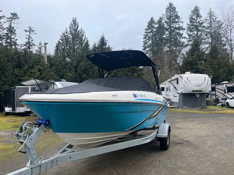 Slide: The Image of 2023 Bayliner VR4 Bowrider OB on trailer, parked outdoors near RVs and trees. - 16
