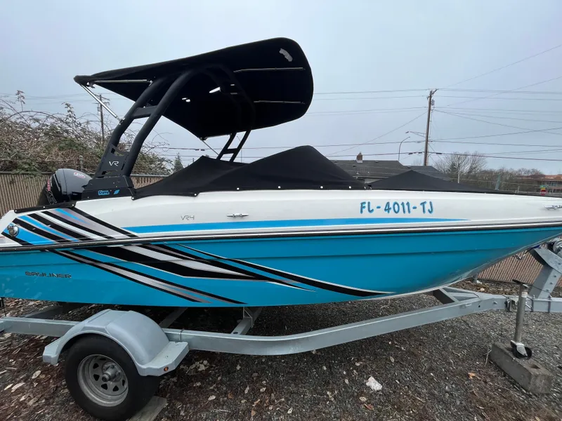 Slide: The Image of 2023 Bayliner VR4 Bowrider OB on trailer, blue and white design, covered, outdoor setting. - 27