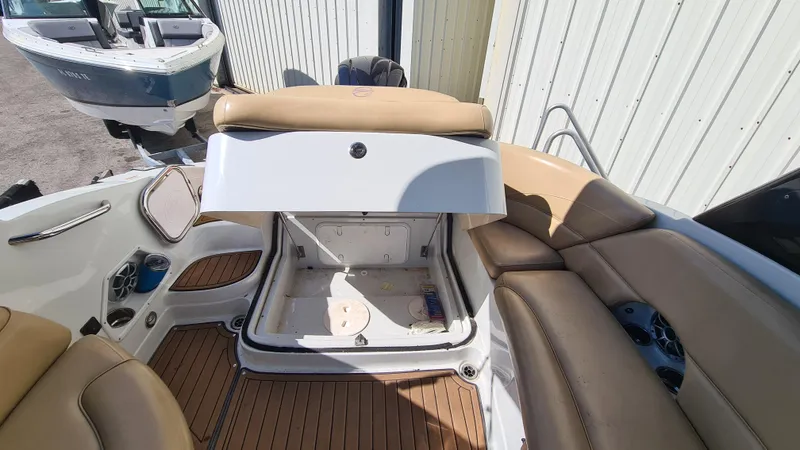 Slide: The Image of 2018 Crownline Eclipse E24 XS boat interior with open storage compartment and tan seating. - 16