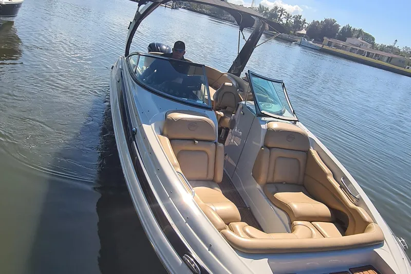 Slide: The Image of 2018 Crownline Eclipse E24 XS boat on calm water, featuring tan seating and a sleek design. - 22