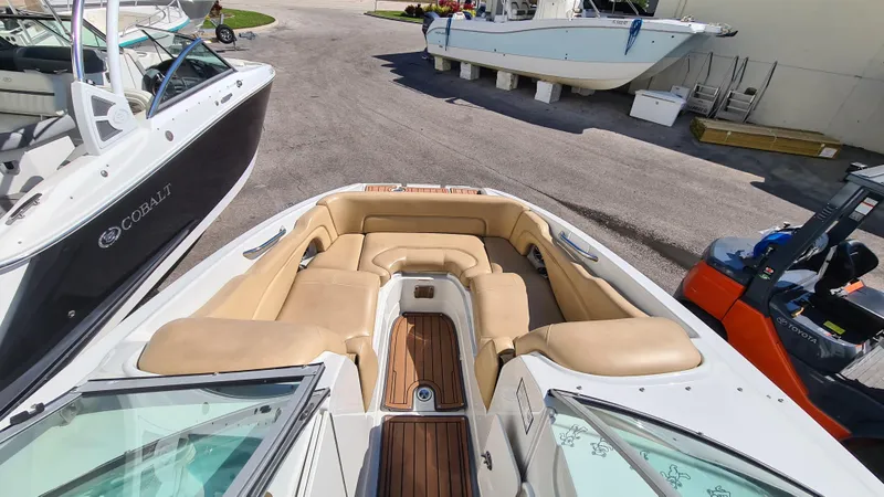 Slide: The Image of 2018 Crownline Eclipse E24 XS boat with tan seating and wooden deck, docked beside other boats. - 5