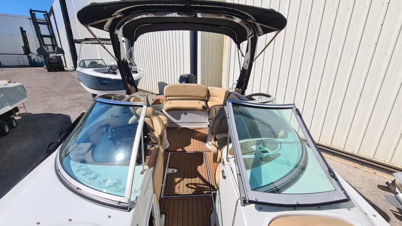 Slide: The Image of 2018 Crownline Eclipse E24 XS boat with open cockpit and seating, docked near a warehouse. - 6