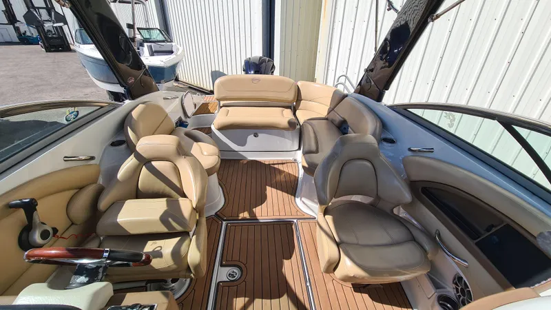 Slide: The Image of 2018 Crownline Eclipse E24 XS boat interior with beige seating and wood flooring. - 7
