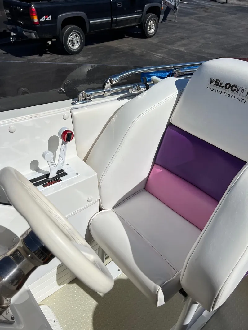 Slide: The Image of 1998 Velocity 260 boat interior with white and purple seating, steering wheel, and controls. - 18