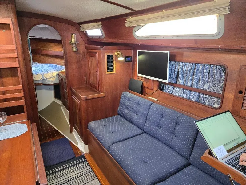 Slide: The Image of Cozy interior of 1991 Freedom F-38 sailboat with blue sofa and wooden accents. - 26