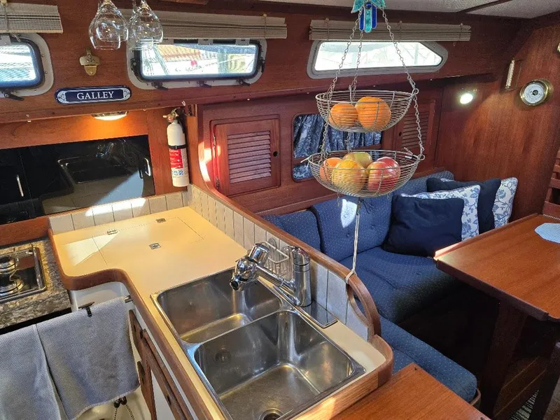Slide: The Image of Cozy 1991 Freedom F-38 yacht galley with double sink, fruit basket, and seating area. - 30