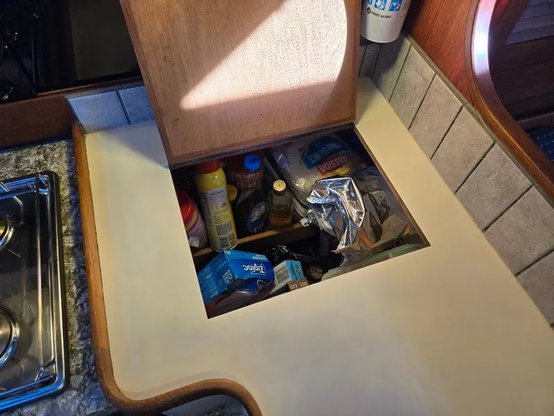 Slide: The Image of Hidden storage compartment in a 1991 Freedom F-38 boat kitchen, filled with various items. - 37