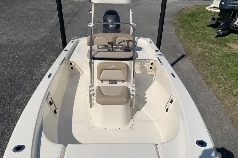 Slide: The Image of 2025 Scout 177 Sport boat with beige seating and center console, parked on pavement. - 27