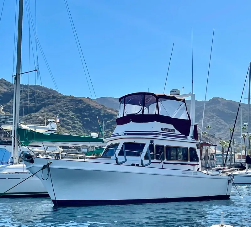 The Image of 1983 Californian 34 yacht docked in a scenic marina with hills in the background. - 0