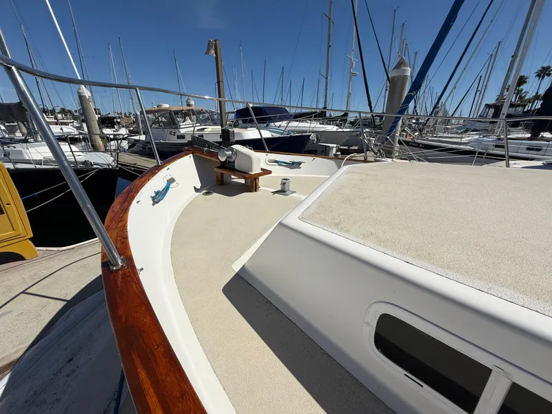 Slide: The Image of 1983 Californian 34 yacht deck with wooden railings, docked at a marina under clear skies. - 11