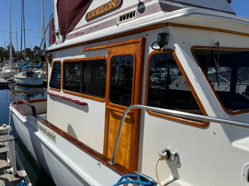 Slide: The Image of 1983 Californian 34 boat docked, featuring wooden accents and "ODELON" nameplate. - 16