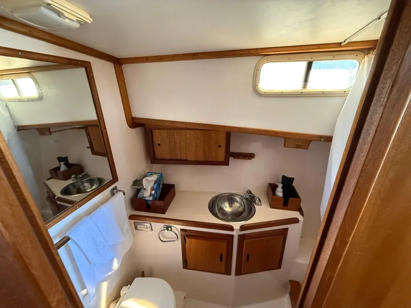 Slide: The Image of 1983 Californian 34 yacht bathroom with wooden cabinets, stainless steel sink, and mirror. - 43