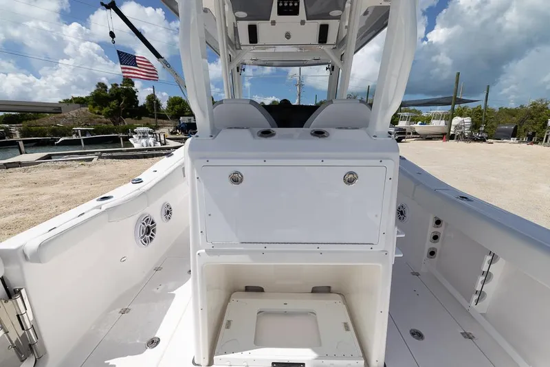 Slide: The Image of 2026 Sea Fox 288 Commander boat interior with seating and storage, docked under a cloudy sky. - 12