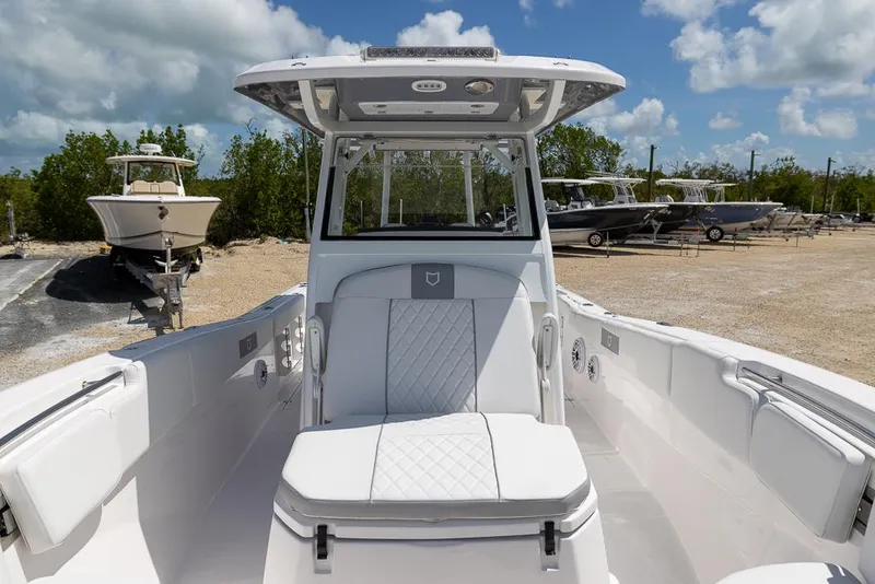 Slide: The Image of 2026 Sea Fox 288 Commander boat interior with white seating, parked on a sunny day. - 23
