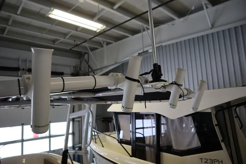 Slide: The Image of 2025 Bayliner 22 CC TROPHY boat in a garage with rod holders. - 22